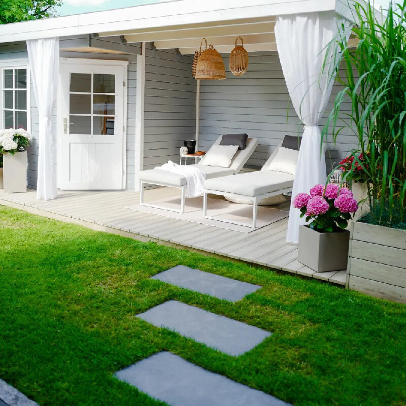 Salotto da giardino con sedie a sdraio e lampade in vimini